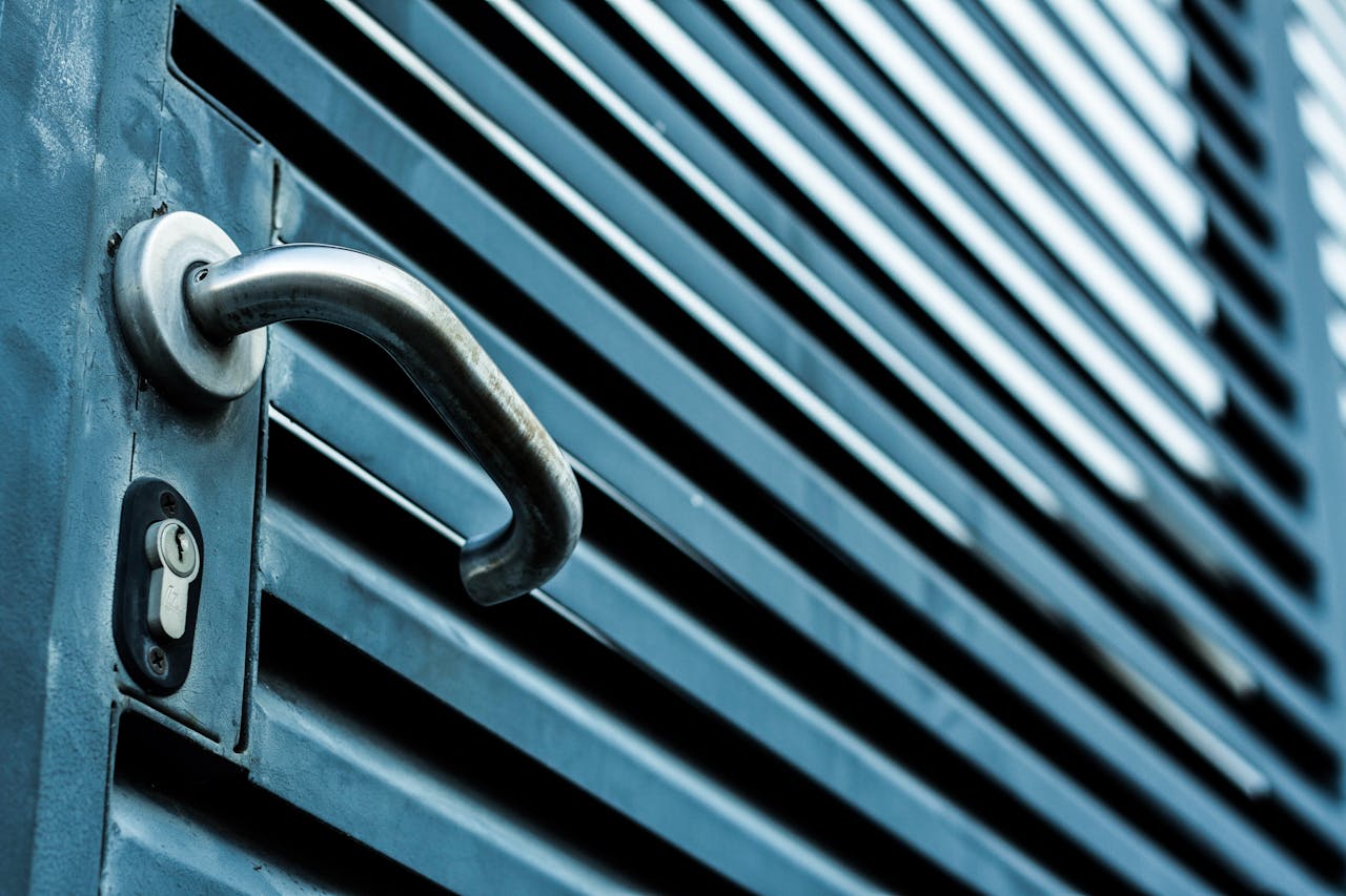 Close-up of a sleek stainless steel door handle and lock on a blue metallic door.
